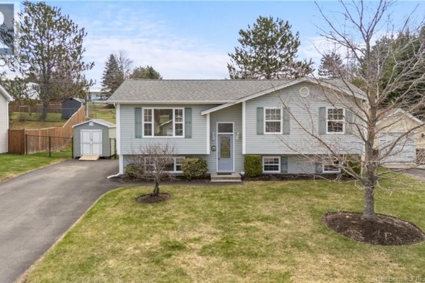 Front exterior of a light blue split-level house with a gray front door and landscaped bushes. - 75 Anik, Dieppe