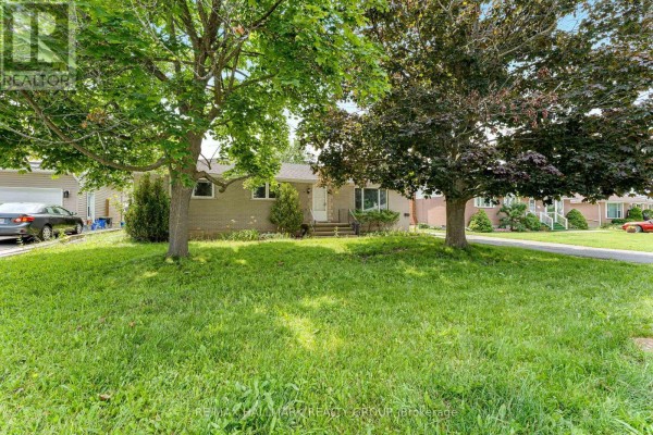 Front view of the house with mature trees in the yard and asphalt driveway. - 75 Briscoe Street, Loyalist