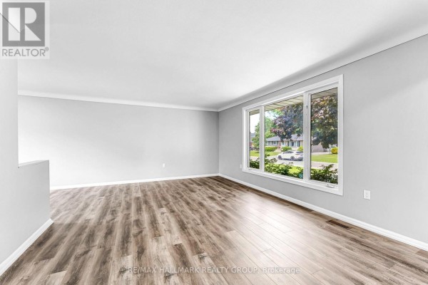 Open-concept living room with light grey walls and wood-look laminate flooring. - 75 Briscoe Street, Loyalist