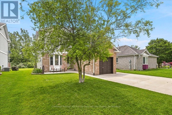 Side view of the house exterior with a large tree in the front yard and green grass. - 75 Edison Crescent, Stratford