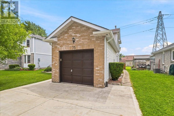 Close-up of the single-car garage door with a brown wood finish and brick detailing on the garage front. - 75 Edison Crescent, Stratford