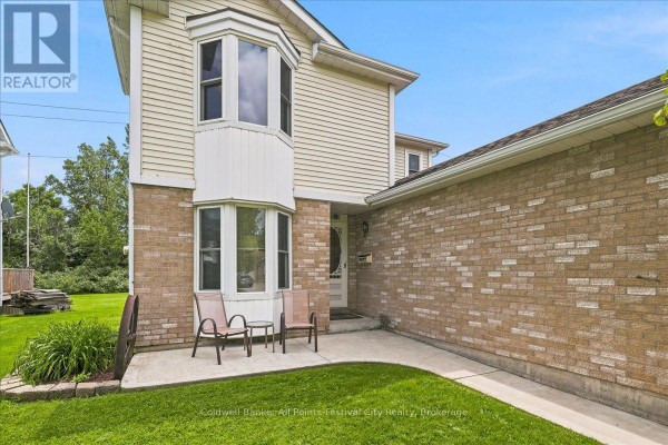 Entrance to the house with two chairs and a small table on a concrete patio beside a brick wall. - 75 Edison Crescent, Stratford