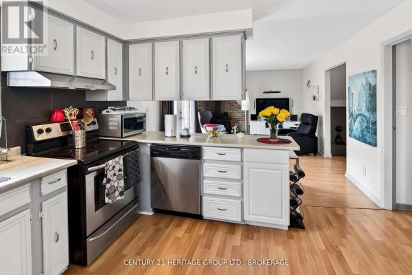 Kitchen with light wood floors, white cabinets, stainless steel appliances, and an island. - 75 Mortensen Drive, Loyalist