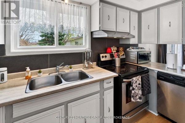 Kitchen sink area with two stainless steel basins and a window overlooking the backyard. - 75 Mortensen Drive, Loyalist