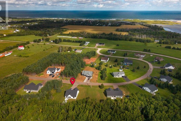 Aerial view of a suburban neighborhood with houses, trees, and ocean in the distance. - 75 Oceanlinks Lane, West St  Peters