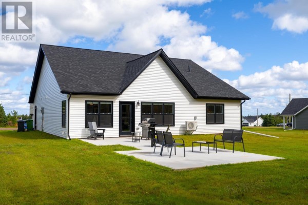 Rear exterior of a white house with a patio, outdoor chairs, and grill. - 75 Oceanlinks Lane, West St  Peters