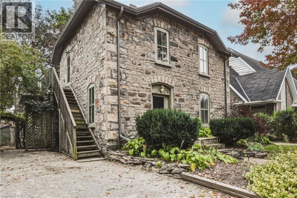 Rear view of the stone house showing an external staircase leading to the upper level and lattice detailing. - 75 Pollock Avenue, Cambridge