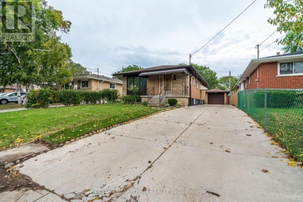 View of the house from the driveway, showing the front facade, lawn, and detached garage. - 75 Purdy Crescent, Hamilton