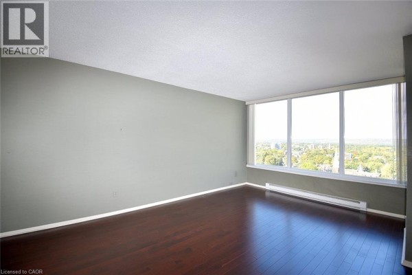 Living room with dark wood floors and large windows offering a view of the city. - 75 Queen Street N Unit# 2007, Hamilton