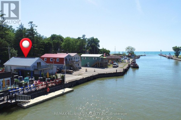 Waterfront commercial buildings on a canal with boats and outdoor dining. - 75 River Road, Lambton Shores