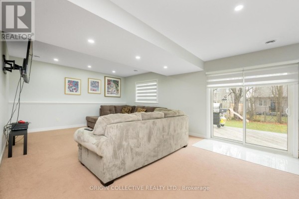 Basement living area with a large sectional sofa, mounted television, and sliding glass doors to the backyard. - 75 Sheffield Street, Southgate