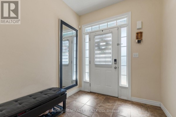 Foyer with beige walls, tiled floor, large mirror, dark bench, and front door. - 75 Sparrow Avenue, Cambridge