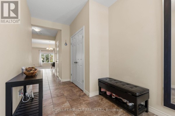 Interior hallway with beige walls, tiled floor, dark console table, bench, and doors. - 75 Sparrow Avenue, Cambridge