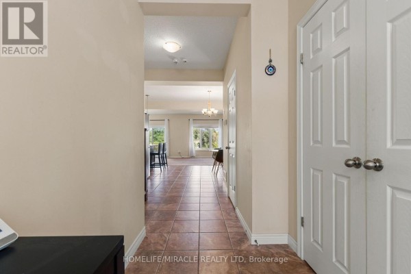 Hallway view into an open-concept living area with tiled floors and neutral walls. - 75 Sparrow Avenue, Cambridge