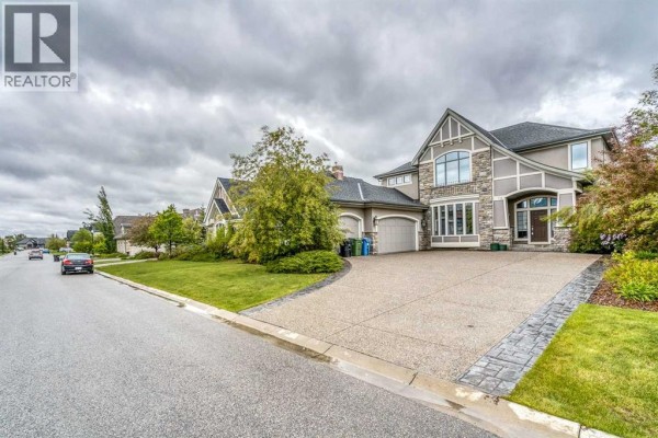 Exterior of a large, modern house with a stucco and stone facade and a double garage. - 75 Wentworth Terrace Sw, Calgary