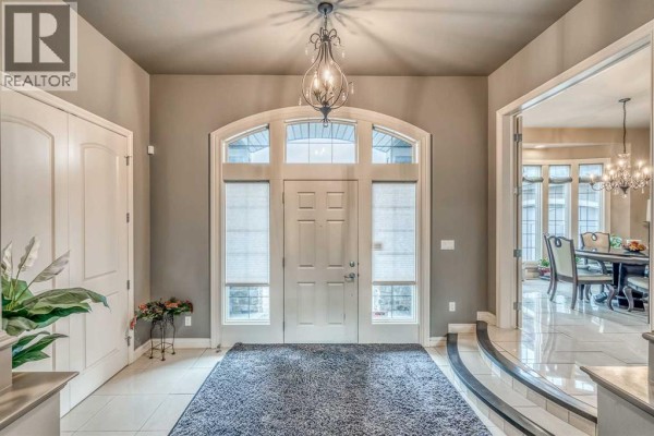 Front entryway with a white door, arched transom window, tile flooring, and a crystal chandelier. - 75 Wentworth Terrace Sw, Calgary