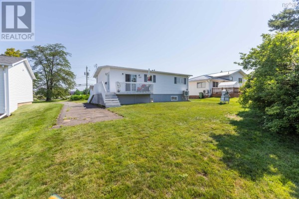 Rear exterior of a white bungalow with a deck, lawn, and trees. - 75 Willow Street, Amherst