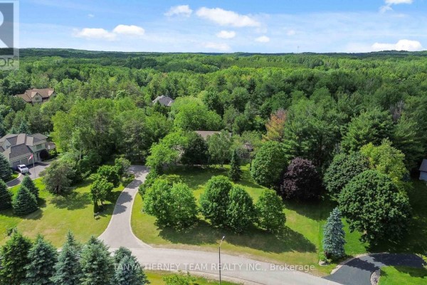 Aerial view of a large house nestled amongst dense green forest with surrounding properties visible. - 75 Woodbridge Circle, Scugog