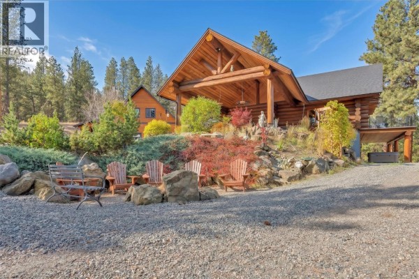 Outdoor seating area with wooden chairs and a fire pit next to a log home, with mature trees and shrubs. - 750 Cedar Creek Road, Princeton