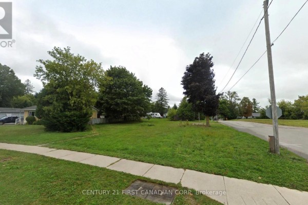 Vacant lot with green grass, trees, a sidewalk, and a paved road at the edge. - 750 Havelock Street N, Huron Kinloss