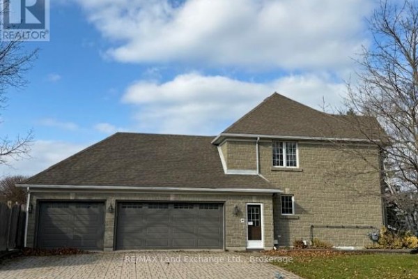 Front view of the house with a three-car garage, stone exterior, and a paved driveway. - 750 Mcpherson Crescent, Kincardine