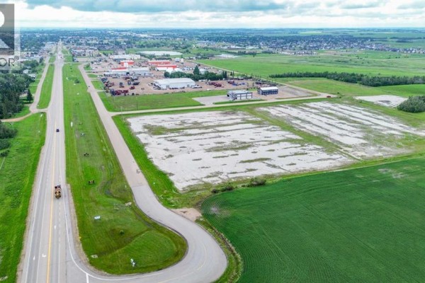 View of the vacant lot with snow, looking towards commercial areas and roads in the distance. - 7501 50 Avenue, Stettler