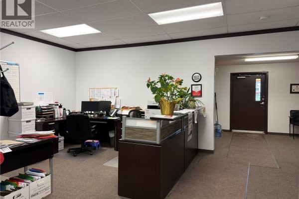 View of office space with a reception desk, computers, and filing cabinets, beige carpet. - 751 7th Avenue W, Melville