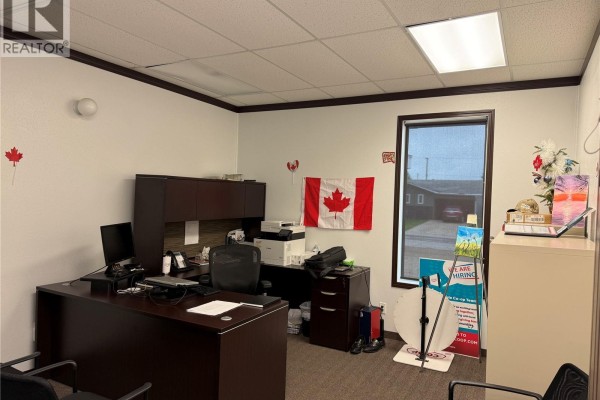 Office interior with a desk, computer, filing cabinets, and a Canadian flag on the wall. - 751 7th Avenue W, Melville