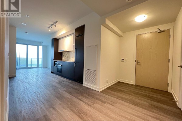 Open concept living area with a modern kitchen, wood floors, and large windows with a city view. - 7510 - 55 Cooper Street, Toronto