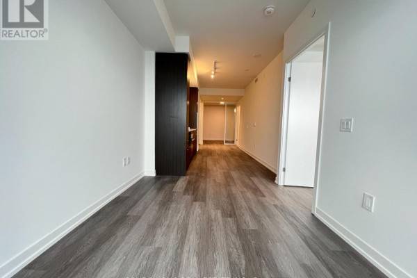 Hallway leading to the living area, showing a dark wood built-in cabinet and a closed white door. - 7510 - 55 Cooper Street, Toronto
