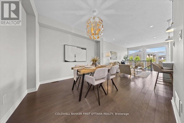 Kitchen island with sink, stainless steel refrigerator, and dining area. - 754 Brian Good Avenue, Ottawa