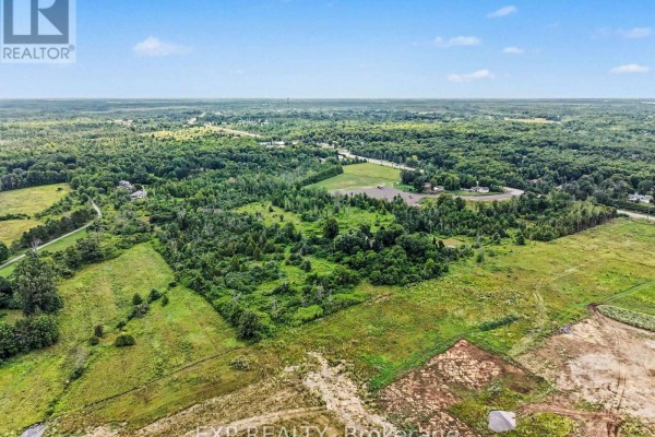 Aerial view of 7540 Highway 15 Highway E, Beckwith, featuring open fields, wooded areas, and distant construction. - 7540 Highway 15 Highway E, Beckwith