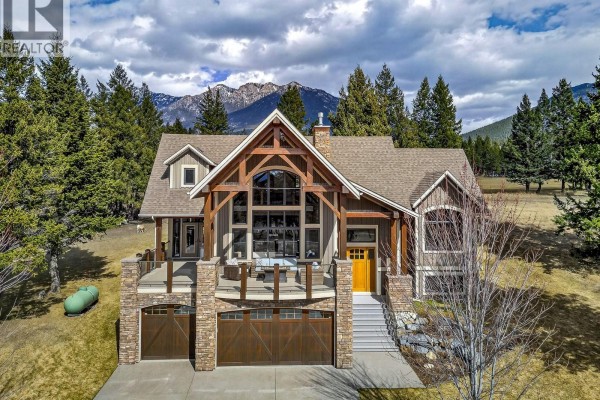Spacious mountain home with a grand entrance, large windows, and attached garage on a sunny day. - 7540 Springs Terrace, Radium Hot Springs