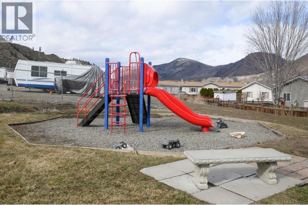 Outdoor playground with red slide and climbing structure. - 7545 Dallas Drive Unit# 54, Kamloops