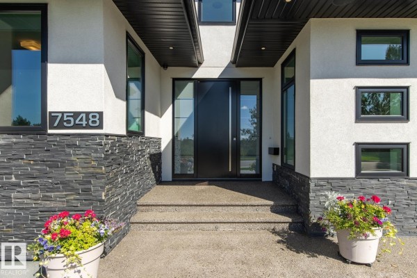 Close-up of the front entrance with a black double door and large planters. - 7548 110 Av Nw, Edmonton