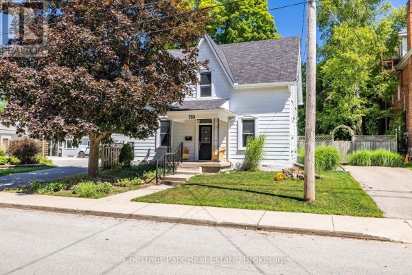 Front porch of a house with black door, stained glass window, black railings, and wicker chairs. - 755 4th Avenue E, Owen Sound