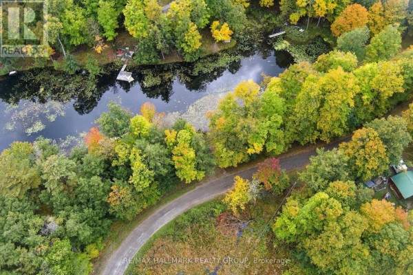 Aerial view of a winding dirt road through a wooded area with autumn foliage. - 755 Indian Lake Road N, Rideau Lakes