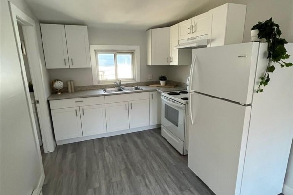 Updated kitchen with white cabinets, light grey laminate flooring, and white appliances. - 755 Ontario Street, Sudbury