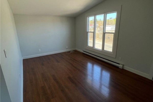 Bedroom with dark hardwood floors, light grey walls, and a large window. - 755 Ontario Street, Sudbury