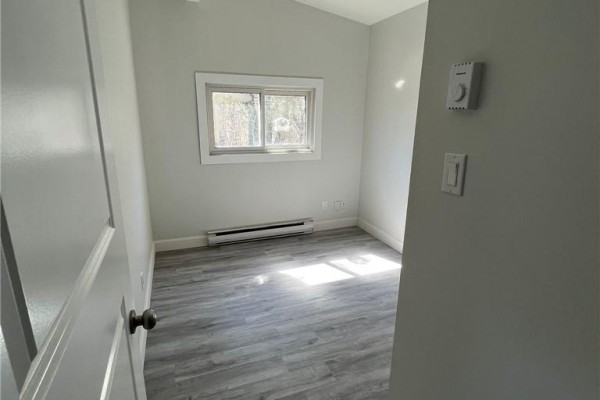 Small bedroom with light grey laminate flooring, light grey walls, and a window. - 755 Ontario Street, Sudbury