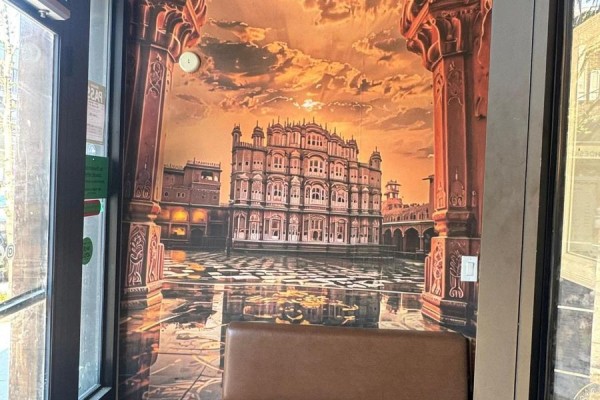 Interior wall features a large mural of an Indian palace and courtyard with a brown leather bench. - 755 Queen Street E, Toronto