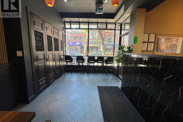 Dining area with bar stools at a window counter and a view of Queen Street East. - 755 Queen Street E, Toronto