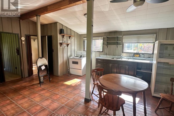 Interior room showing a kitchen area with white stove, dark cabinets, and dining table. - 755 Shore Lane, Wasaga Beach