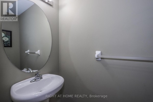 Powder room with a pedestal sink, round mirror, and towel bar. - 756 Hedgerow Place, London North
