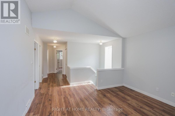 Upstairs hallway with multiple doors and vaulted ceiling, leading to stairs. - 756 Hedgerow Place, London North