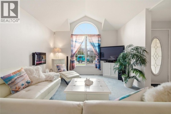 Living room with a sectional sofa, mirrored closet doors, and a dining area visible through a doorway. - 756 Springrose Way, Kelowna