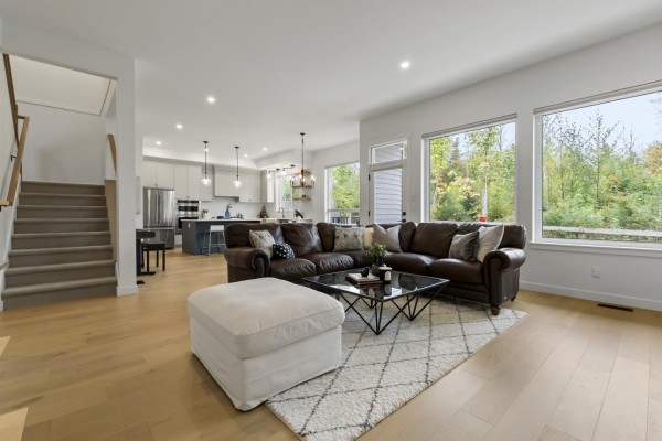 Open concept living room and kitchen with a large sectional, fireplace, and island. - 7567 196a Street, Langley