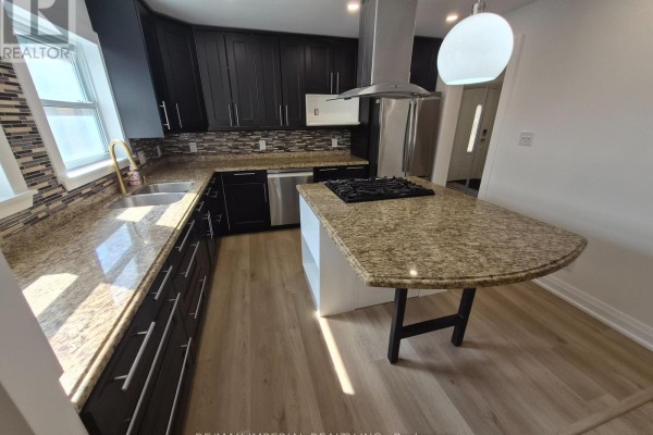 A modern kitchen with dark wood cabinets, granite countertops, stainless steel appliances, and an island with a gas cooktop. - 757 Pam Crescent, Newmarket