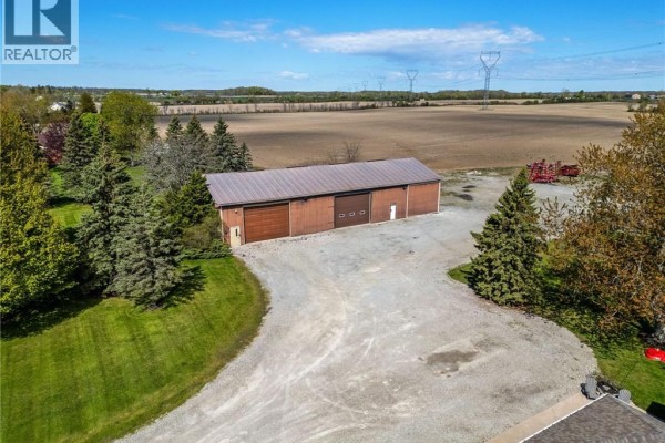 Side view of a brick bungalow with a covered patio area and manicured landscaping. - 759 Concession 14 Walpole Road, Hagersville