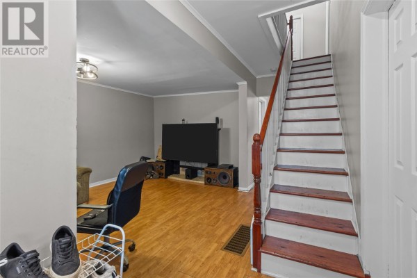 Interior living room with a large screen TV, wooden floors, and a staircase. - 76-78 Goodridge Street, St  John S